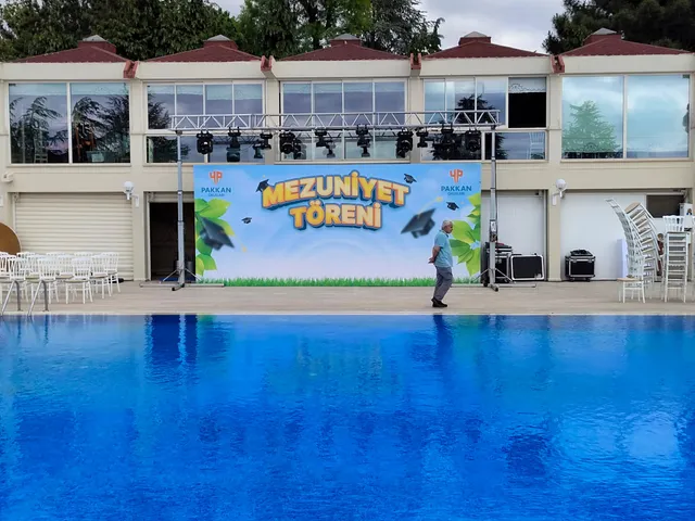 Pakkan Okulları mezuniyet fonu — yakın görünüm — Mezuniyet töreninin baskılı sahne arkasını yakından gösteren uygulama fotoğrafı.