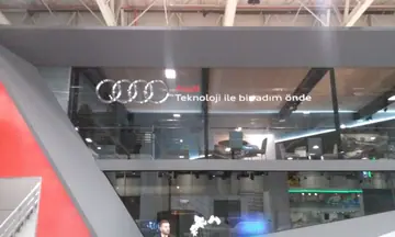 Audi fuar alanı marka uygulaması — Üst kattaki cam yüzeyde marka logosu ve yazı uygulaması.